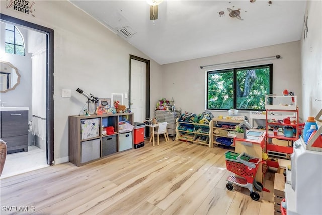 playroom featuring vaulted ceiling, wood finished floors, visible vents, and plenty of natural light