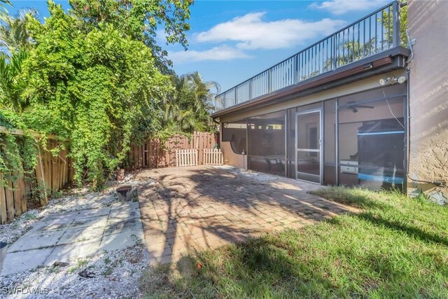 exterior space featuring a sunroom, a patio, a fenced backyard, and a balcony