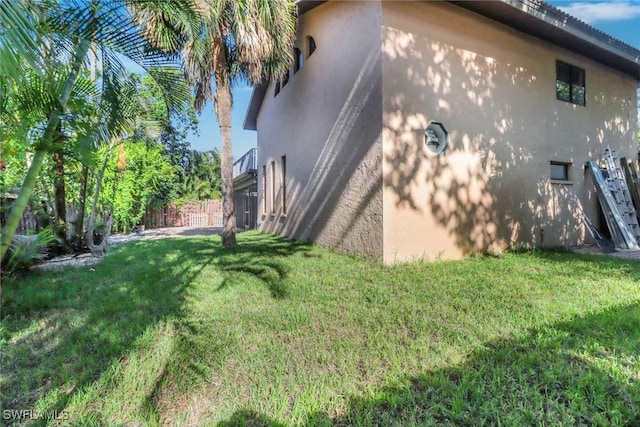 view of home's exterior featuring a lawn, stucco siding, and fence