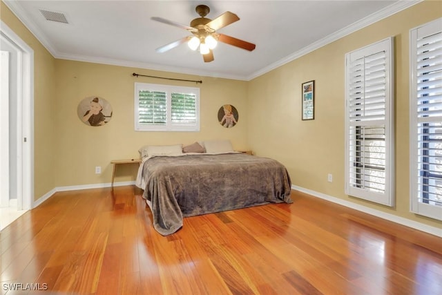 bedroom featuring baseboards, visible vents, a ceiling fan, wood finished floors, and ornamental molding