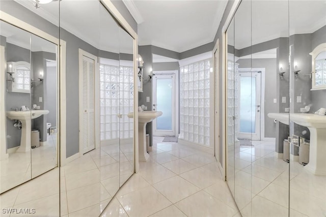 bathroom with a closet, tile patterned floors, baseboards, and ornamental molding