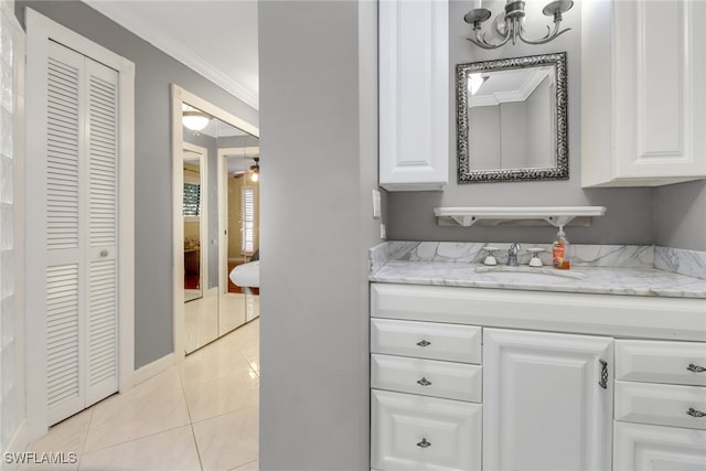 bathroom with tile patterned flooring, vanity, a closet, crown molding, and baseboards