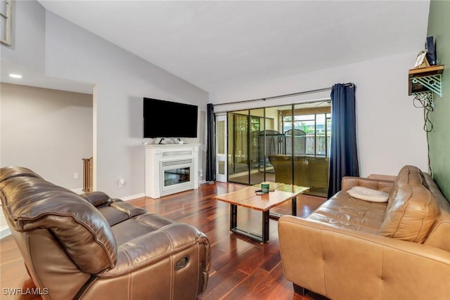 living area featuring vaulted ceiling, a glass covered fireplace, and wood finished floors