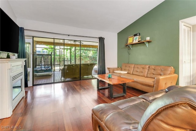 living area with a glass covered fireplace, vaulted ceiling, and wood finished floors
