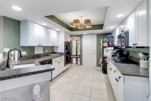 kitchen featuring a raised ceiling, white cabinetry, a sink, and black appliances