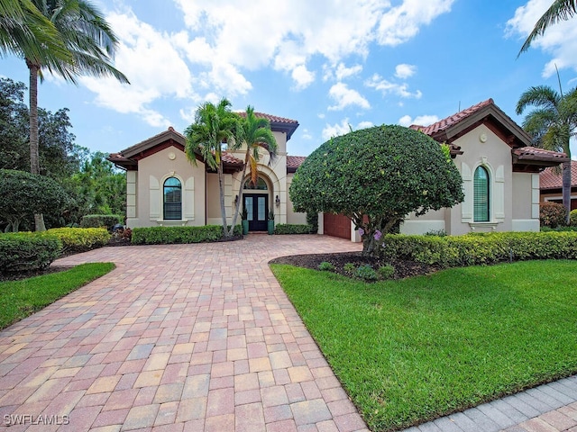 mediterranean / spanish-style house featuring french doors, a tile roof, decorative driveway, and stucco siding