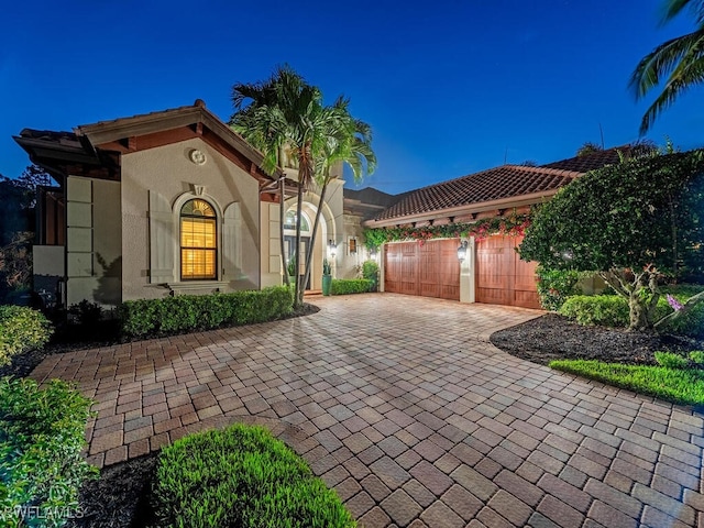 view of front of house with a garage, decorative driveway, and stucco siding