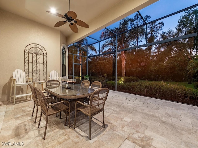 view of patio featuring a lanai, outdoor dining space, and ceiling fan