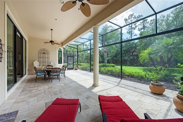 view of patio with outdoor dining area, glass enclosure, and ceiling fan