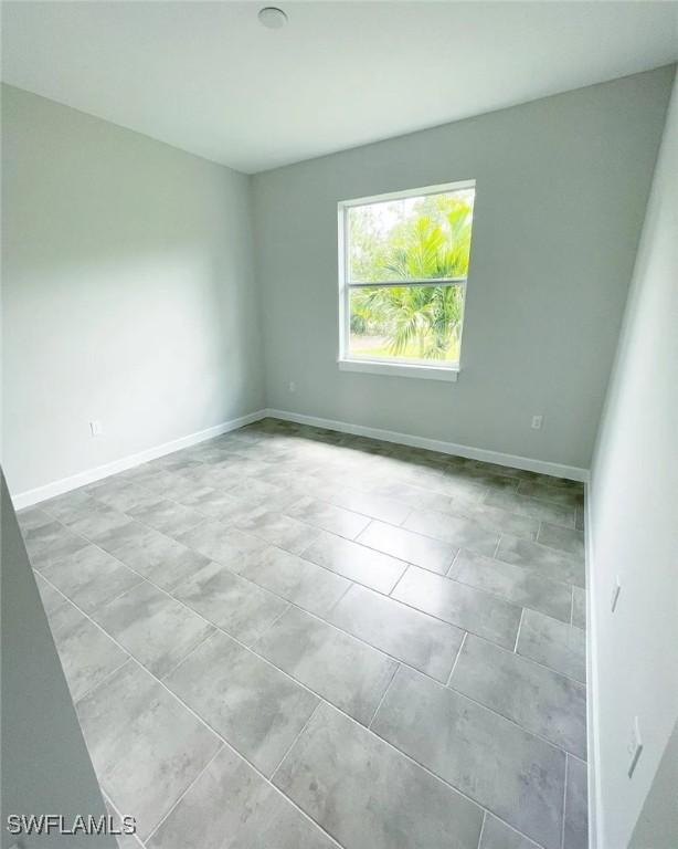 empty room with light tile patterned floors and baseboards