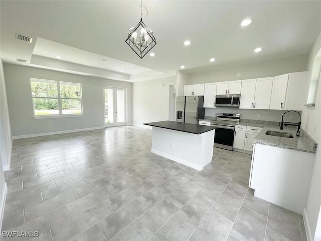 kitchen with visible vents, a kitchen island, a sink, stainless steel appliances, and open floor plan