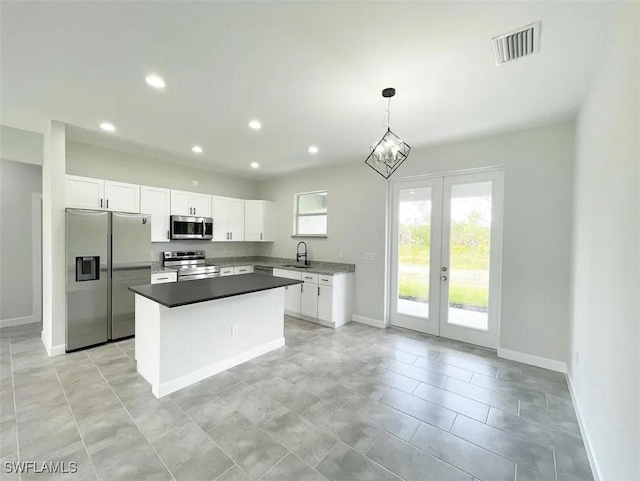 kitchen with white cabinets, visible vents, appliances with stainless steel finishes, a sink, and baseboards
