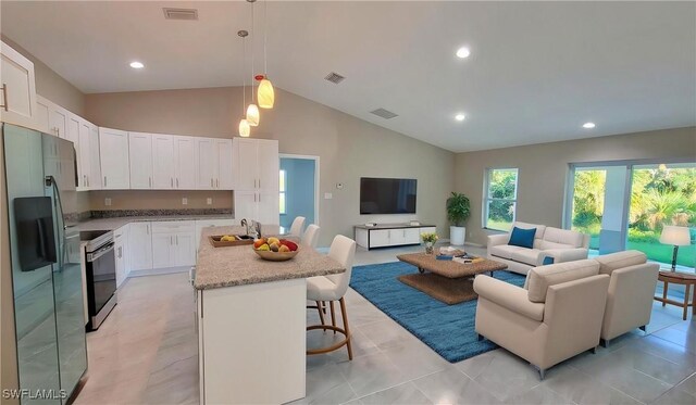 1138 Argosy Rd, Labelle, FL 33935 - kitchen with stainless steel fridge, open floor plan, range with electric stovetop, vaulted ceiling, and a sink