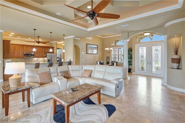 144 SW 54th Ter, Cape Coral, FL 33914 - living room featuring a tray ceiling, ceiling fan with notable chandelier, crown molding, arched walkways, and ornate columns