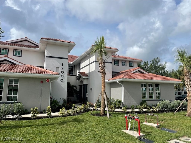 12000 Santaluz Dr Unit 202, Fort Myers, FL 33913 - rear view of property with a tiled roof, a lawn, and stucco siding