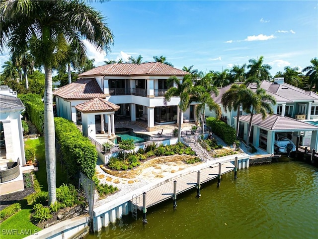 rear view of property with a patio area, a tiled roof, an outdoor pool, and a balcony