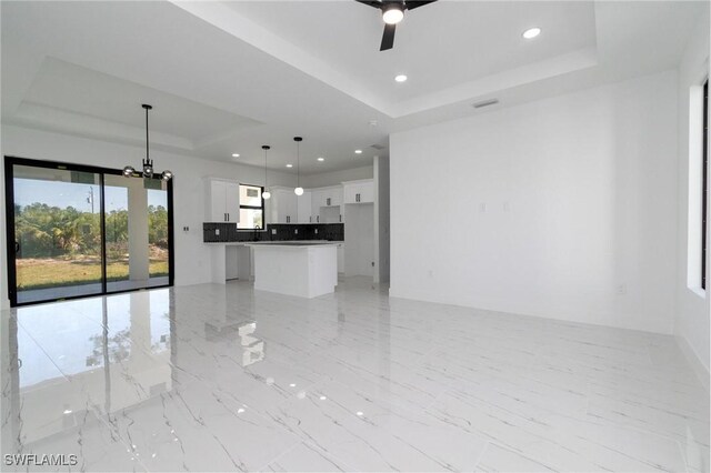 3314 43rd St W, Lehigh Acres, FL 33971 - unfurnished living room with a tray ceiling, recessed lighting, marble finish floor, and ceiling fan with notable chandelier