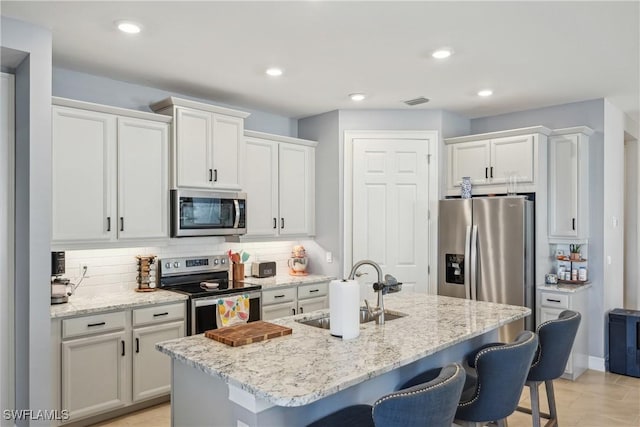 847 Stonewater Lake Ter, Cape Coral, FL 33993 - kitchen with stainless steel appliances, a sink, a kitchen bar, decorative backsplash, and white cabinetry