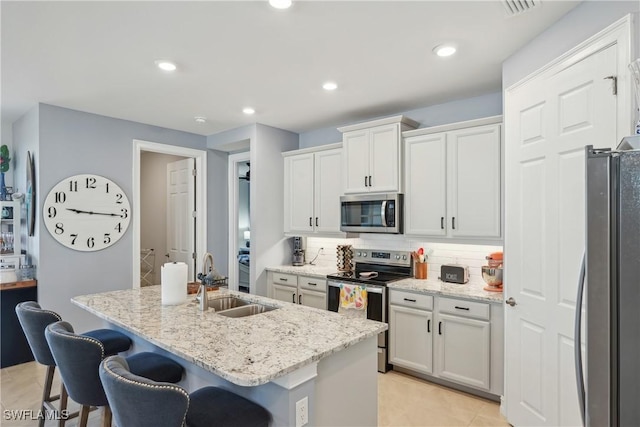 847 Stonewater Lake Ter, Cape Coral, FL 33993 - kitchen with stainless steel appliances, a sink, tasteful backsplash, a breakfast bar area, and a kitchen island with sink