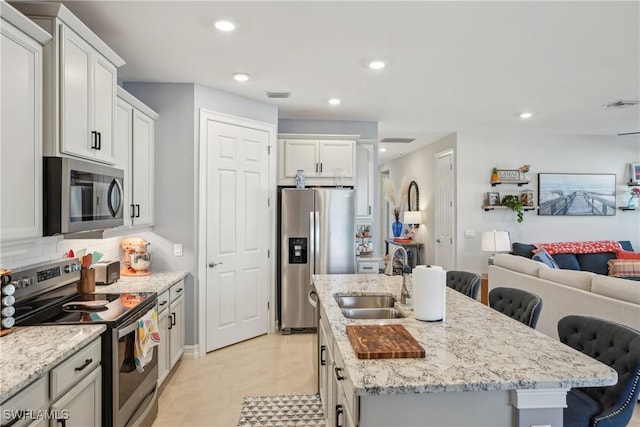 847 Stonewater Lake Ter, Cape Coral, FL 33993 - kitchen featuring stainless steel appliances, a sink, open floor plan, a kitchen island with sink, and a kitchen breakfast bar