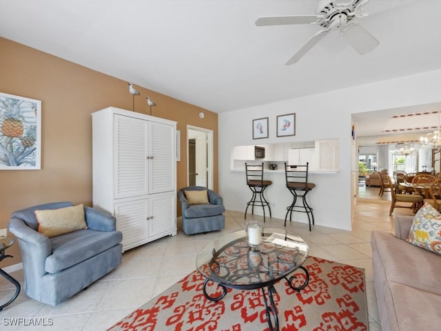 living area featuring ceiling fan with notable chandelier and light tile patterned floors