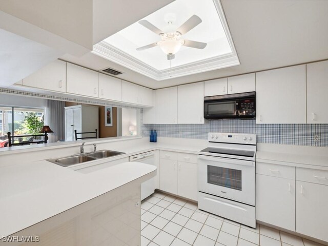 kitchen with white appliances, light countertops, a tray ceiling, decorative backsplash, and a sink
