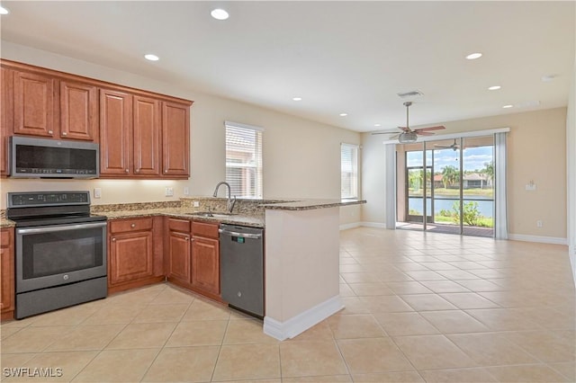 10486 Winged Elm Ln, Fort Myers, FL 33913 - kitchen with appliances with stainless steel finishes, a peninsula, a ceiling fan, light tile patterned floors, and light stone counters