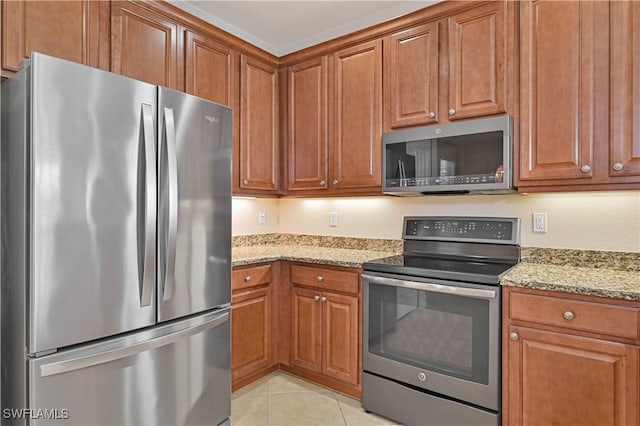 10486 Winged Elm Ln, Fort Myers, FL 33913 - kitchen with appliances with stainless steel finishes, light stone countertops, brown cabinetry, and light tile patterned floors