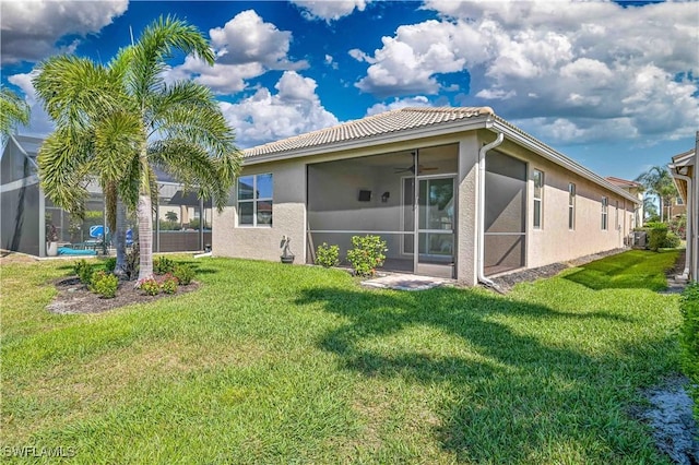 10486 Winged Elm Ln, Fort Myers, FL 33913 - rear view of property with stucco siding, a lawn, a sunroom, a tile roof, and a ceiling fan