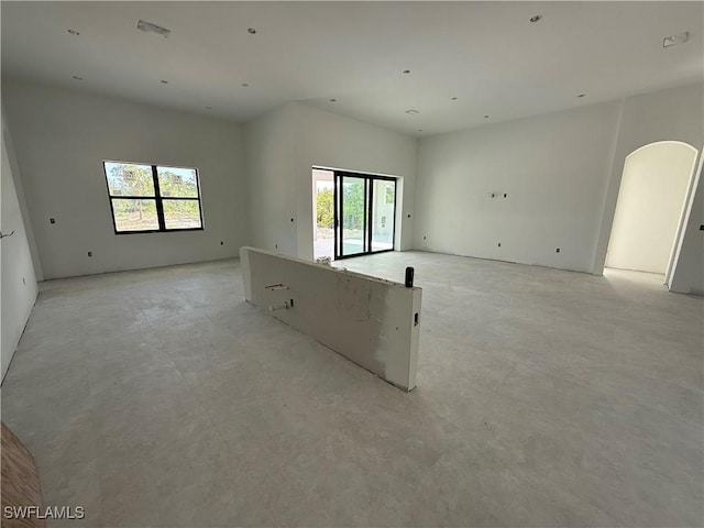2481 24th Ave NE, Naples, FL 34120 - empty room featuring arched walkways, healthy amount of natural light, and concrete floors