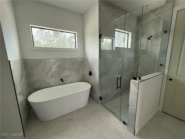 2481 24th Ave NE, Naples, FL 34120 - bathroom with a freestanding tub, a stall shower, tile walls, and wainscoting
