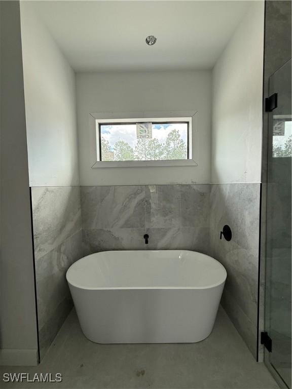 2481 24th Ave NE, Naples, FL 34120 - full bath with tile walls, a freestanding tub, and a shower stall