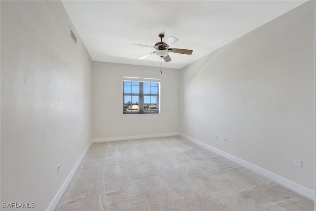 empty room with carpet flooring, a ceiling fan, baseboards, and visible vents