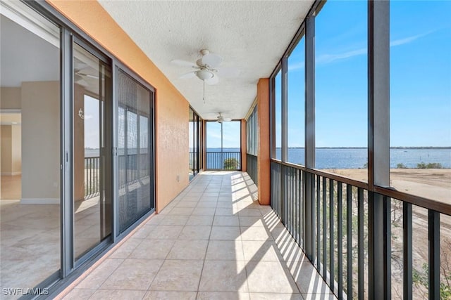 unfurnished sunroom featuring a water view and ceiling fan