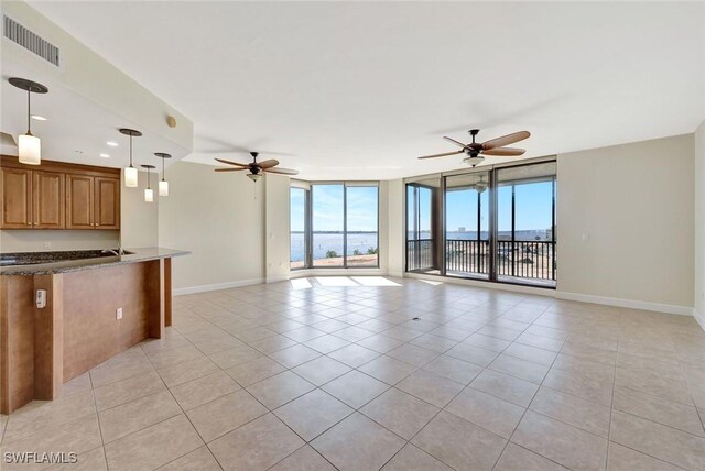 unfurnished living room featuring a healthy amount of sunlight, ceiling fan, expansive windows, and visible vents