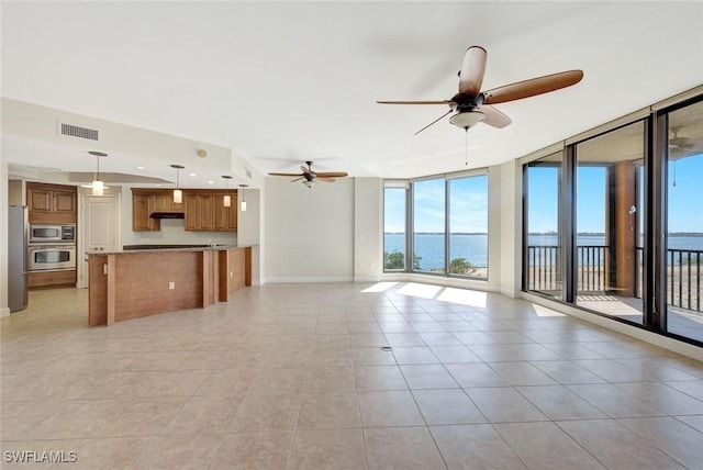 unfurnished living room featuring visible vents, a ceiling fan, a healthy amount of sunlight, and expansive windows