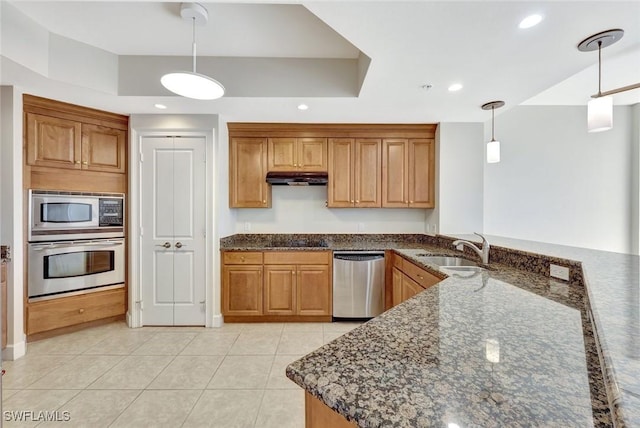 kitchen with brown cabinetry, hanging light fixtures, a sink, under cabinet range hood, and stainless steel appliances