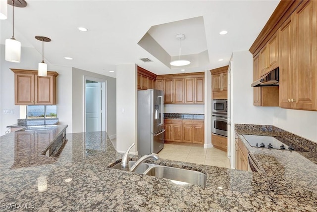 kitchen with appliances with stainless steel finishes, a sink, dark stone counters, under cabinet range hood, and visible vents