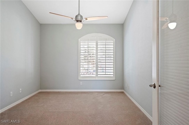 carpeted empty room with a ceiling fan and baseboards