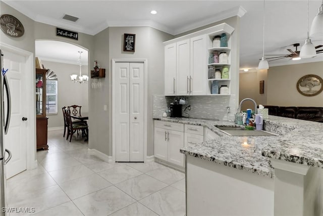 kitchen with a sink, open shelves, crown molding, light stone counters, and decorative backsplash