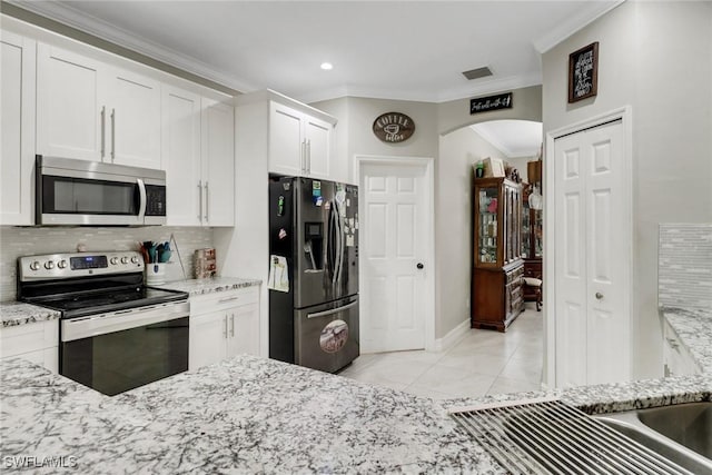 kitchen featuring stainless steel appliances, crown molding, arched walkways, backsplash, and white cabinets