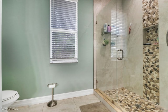 bathroom with a shower stall, baseboards, toilet, and tile patterned flooring
