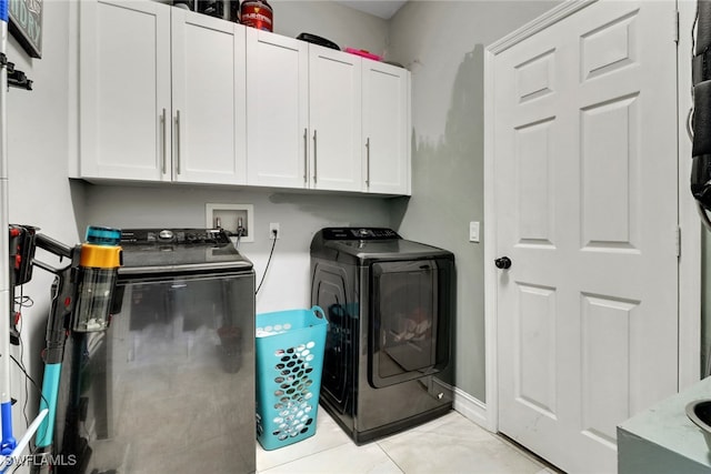 clothes washing area with separate washer and dryer and cabinet space