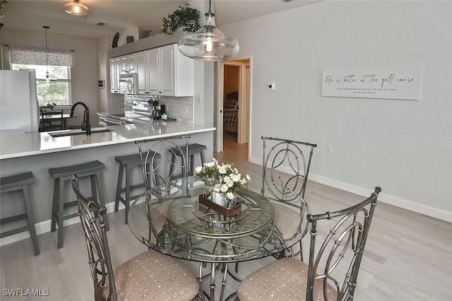dining space featuring light wood-style flooring and baseboards