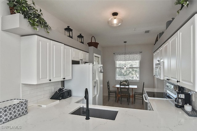 kitchen featuring white appliances, visible vents, white cabinets, a sink, and decorative backsplash