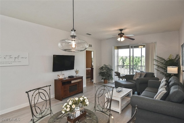 living area with visible vents, ceiling fan, light wood finished floors, and baseboards