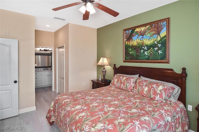 bedroom featuring visible vents, baseboards, a sink, connected bathroom, and wood finished floors