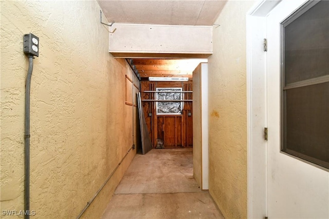 corridor with concrete flooring and a textured wall