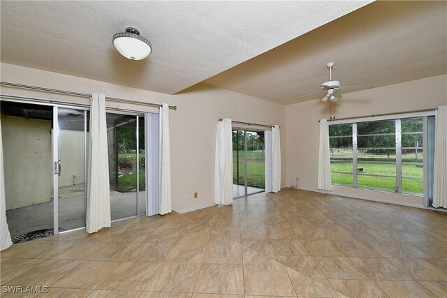 empty room featuring a textured ceiling, a ceiling fan, and baseboards