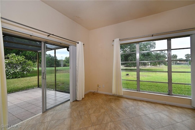doorway featuring a healthy amount of sunlight, baseboards, and light tile patterned floors
